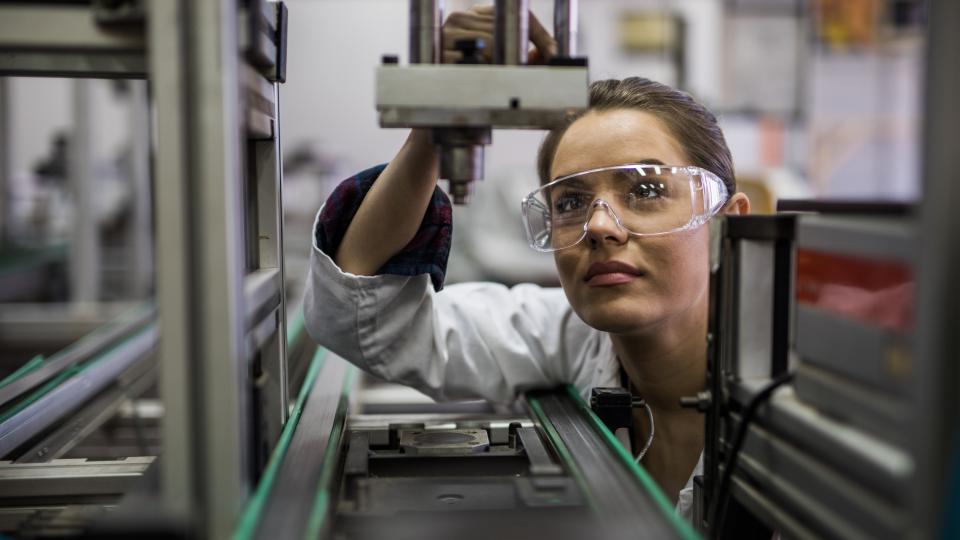 A woman is standing in front of a microscope