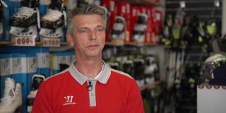 Peter Glinka steht vor einer Wand mit Schlittschuhen.