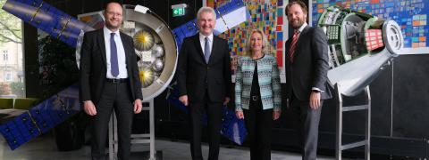 Prof. Dr. Andreas Pinkwart mit drei weiteren Personen vor Modellen aus der Raumfahrt