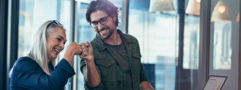 Frau und Mann stehen an einem Stehtisch und klatschen sich ab.