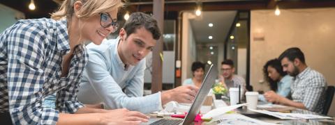 Frau und Mann mit Laptop und Papierdokumenten am Schreibtisch im Büro