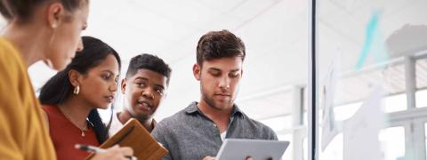 Zwei Frauen und zwei Männer stehen nebeneinander, ein Mann hält ein Tablet in Händen, die beiden Frauen Notizhefte