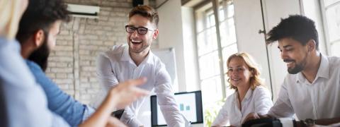 Zwei Frauen und drei Männer bei einem Meeting in einem Meetingraum