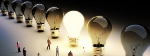 Eine leuchtende Glühbirne und viele Menschen die darauf zugehen